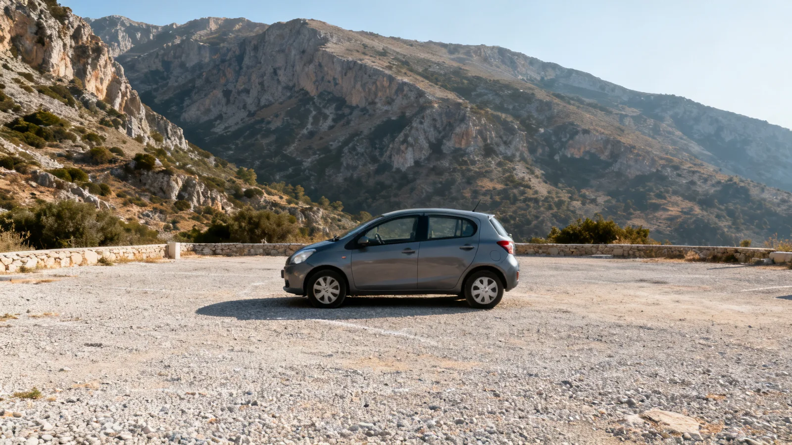 An unbranded compact car in a gravel mountain parking area