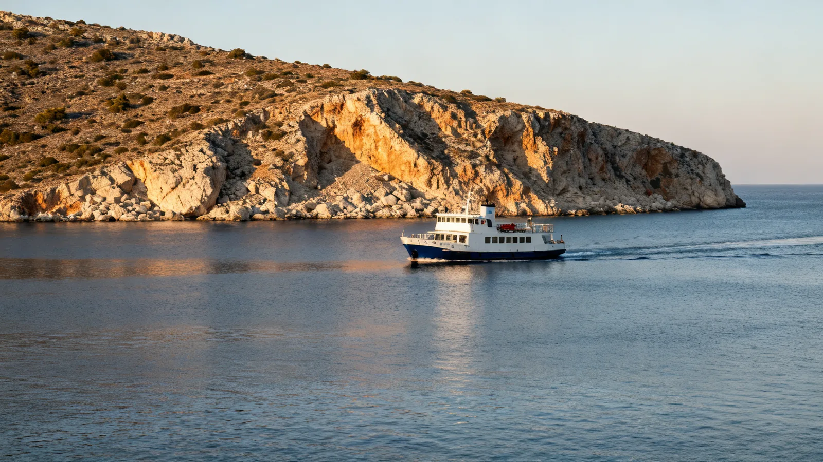 A small passenger ferry passing a rocky headland